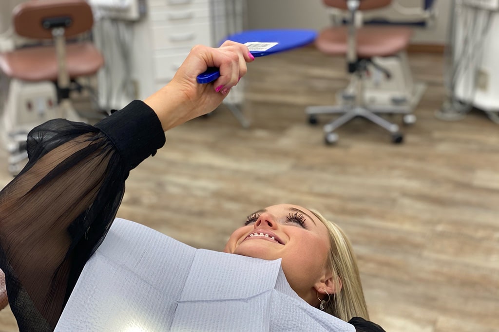 A patient checking their teeth in a mirror | Harwell & Cook Orthodontics