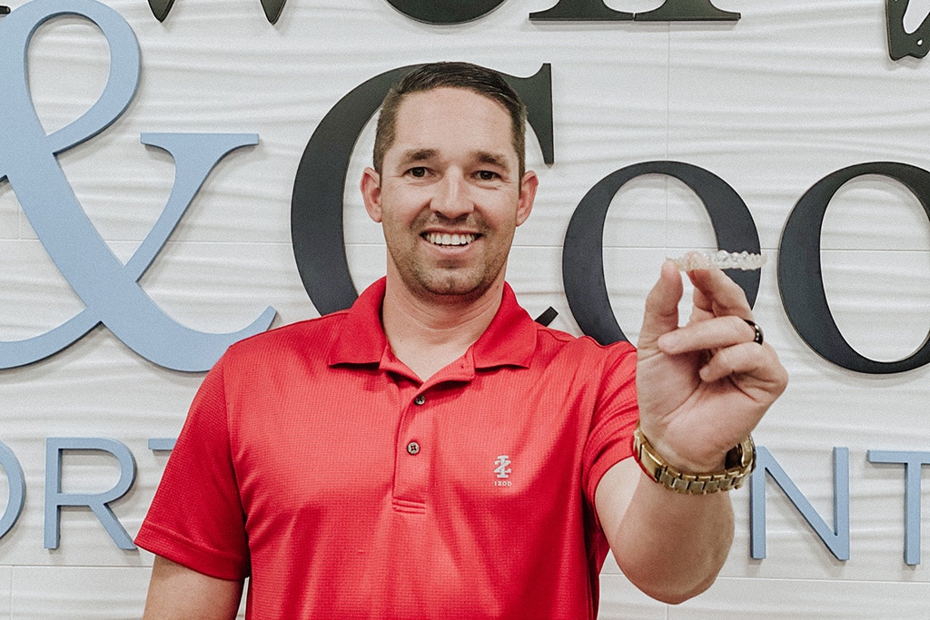 A smiling man in a red polo shirt | Harwell & Cook Orthodontics