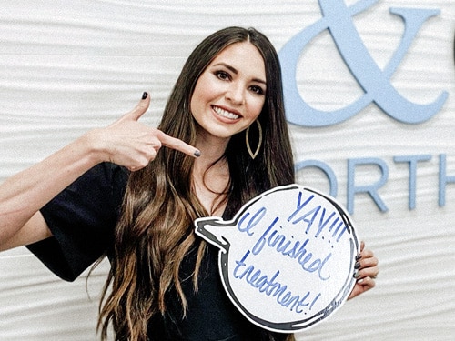 A woman holding a speech bubble sign. | Harwell & Cook Orthodontics