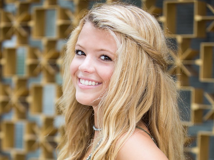 A smiling young woman with long blonde hair | Harwell & Cook Orthodontics