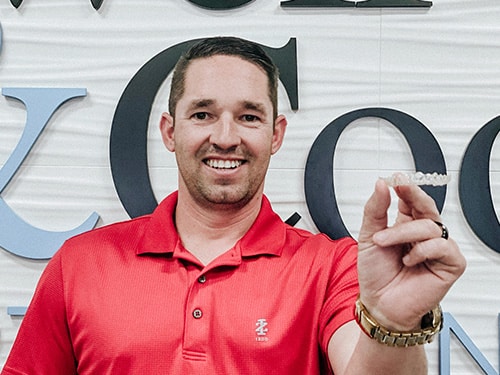 A smiling man in a red polo shirt | Harwell & Cook Orthodontics