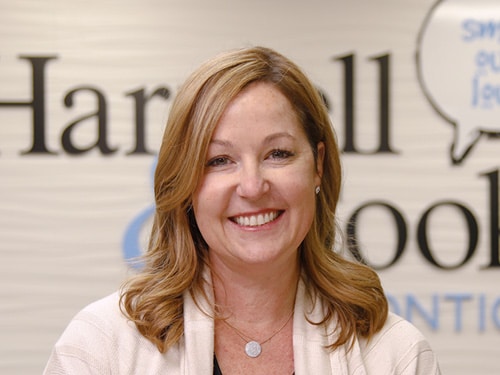 A smiling woman in a white jacket. | Harwell & Cook Orthodontics