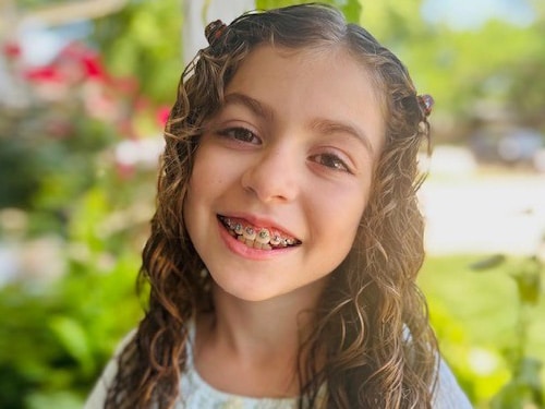 A young girl with curly hair and braces. | Harwell & Cook Orthodontics