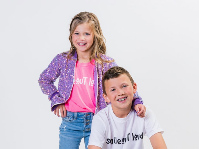 Two smiling children posing together. | Harwell & Cook Orthodontics