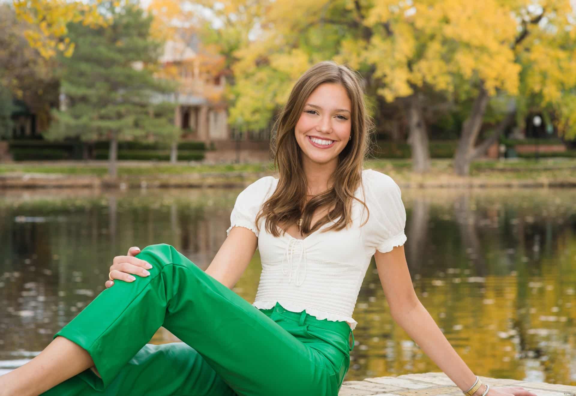 A smiling woman in white and green clothing posing outside. | Harwell & Cook Orthodontics