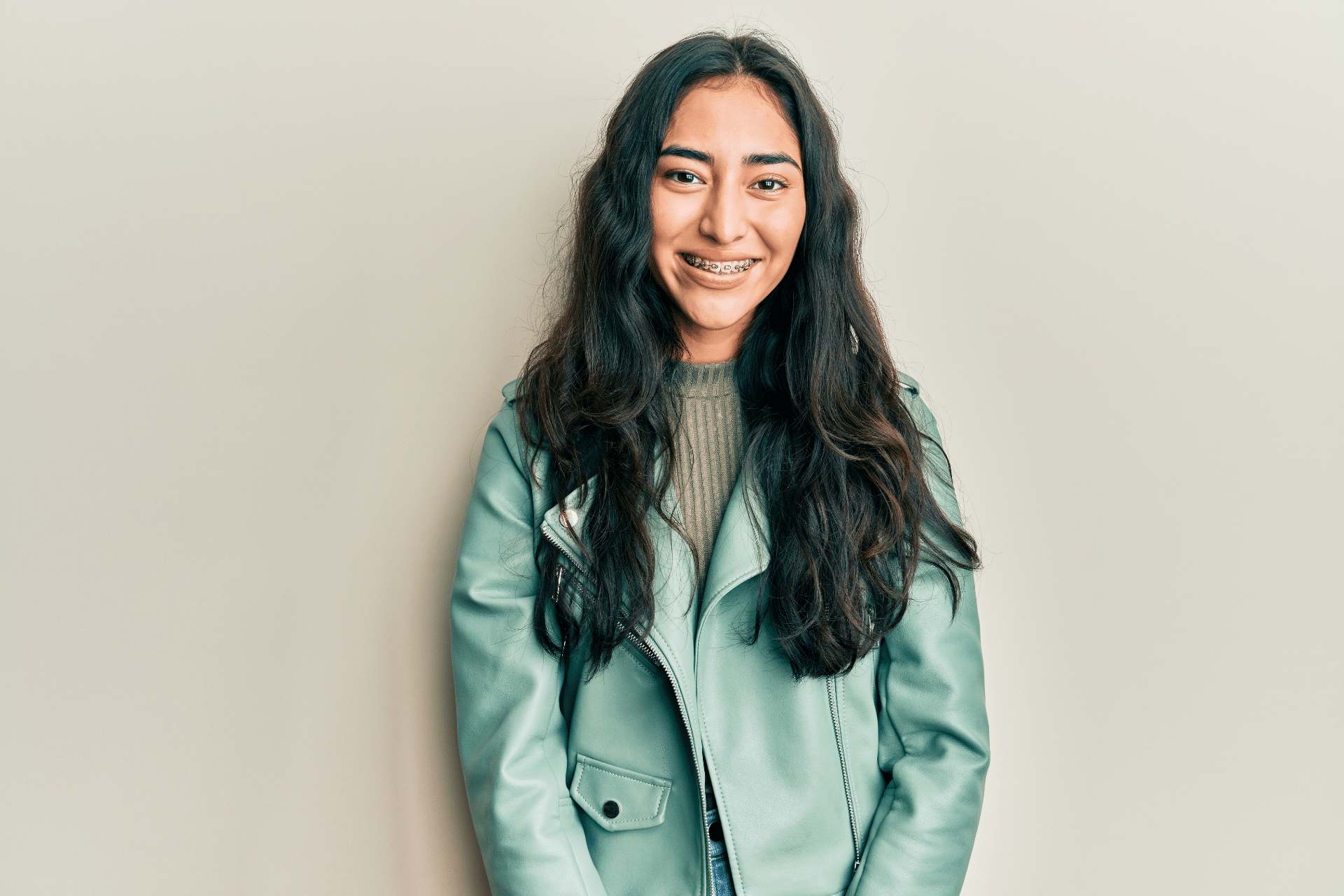Smiling teen wearing metal braces against a neutral background